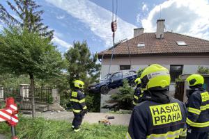 Auto v Praze narazilo do domu. Jeřáb se hasičům docela hodil (VIDEO)